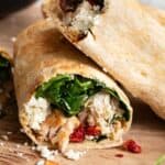 Chicken wraps stacked on top of each other on a cutting board.