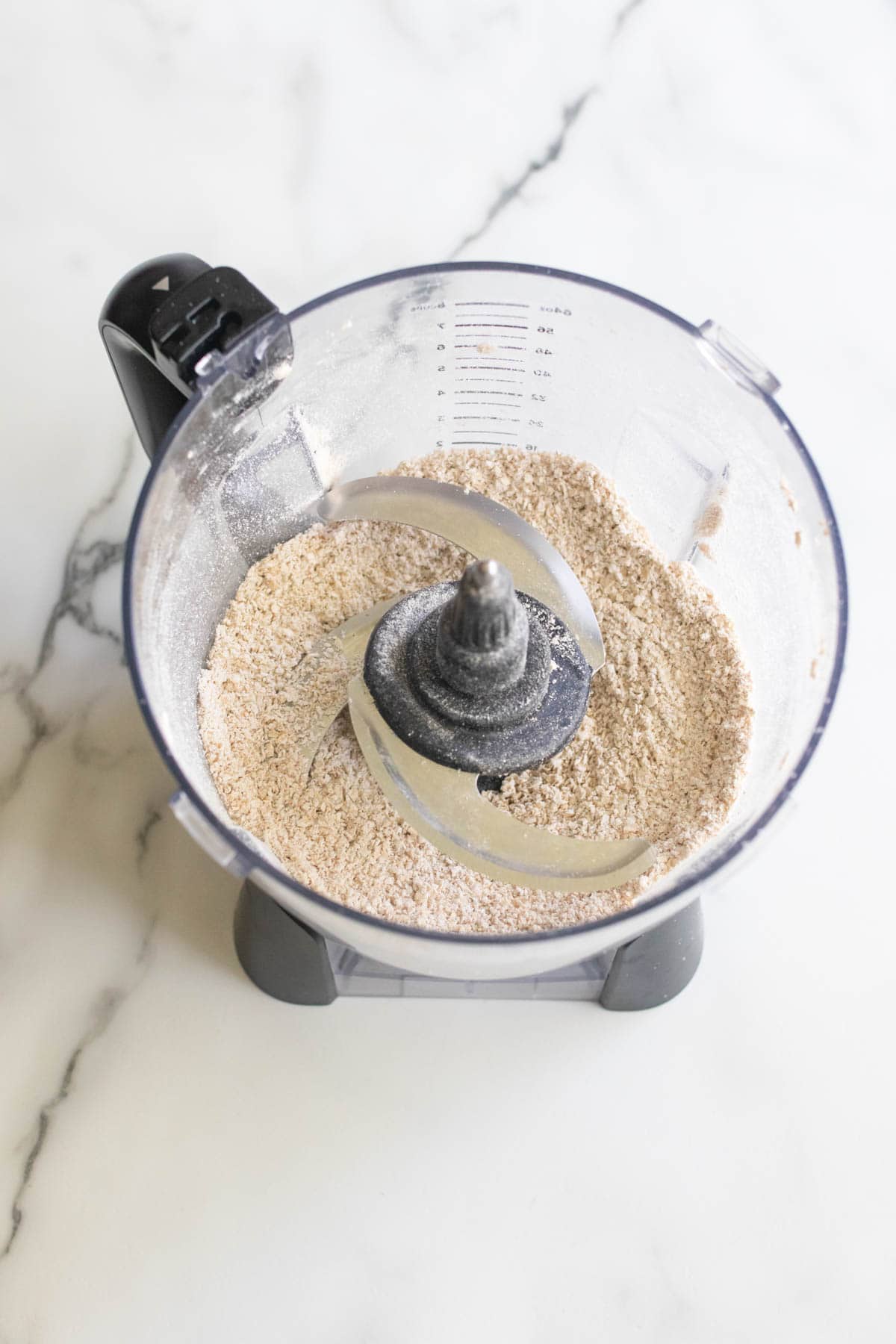 Blending oats in a food processor to make oat flour.