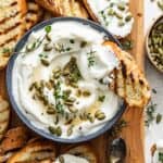 Whipped ricotta in a bowl with grilled bread dipping in.