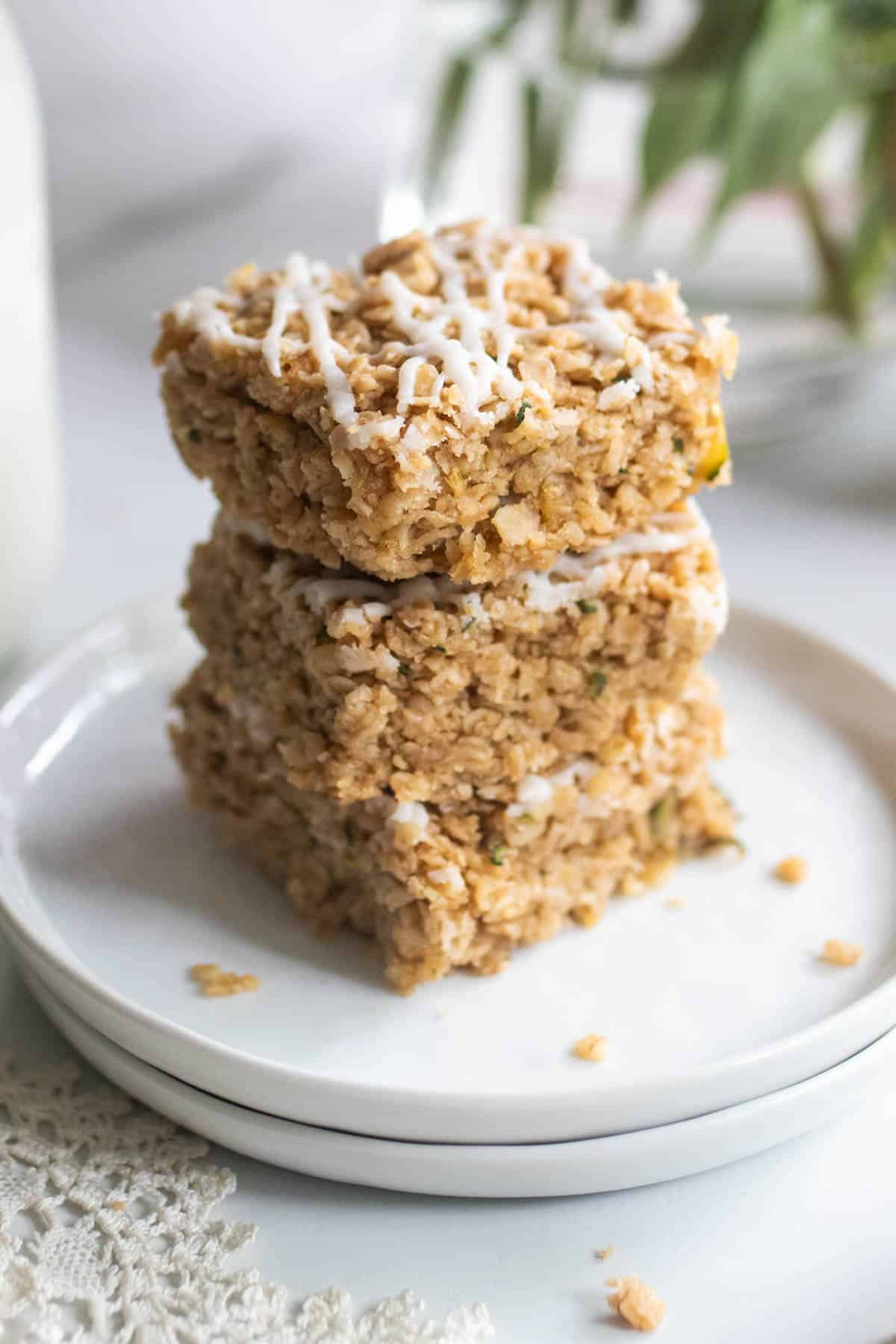 A plate with 3 zucchini bars with oats scattered around the edges.