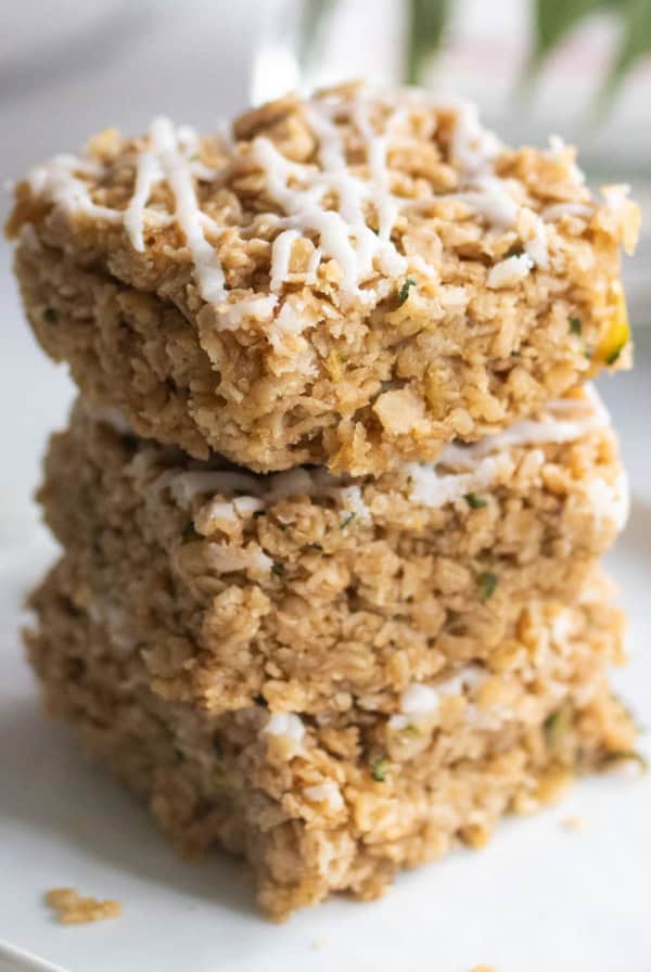 Zucchini bars topped with oats and a white cream cheese drizzle.