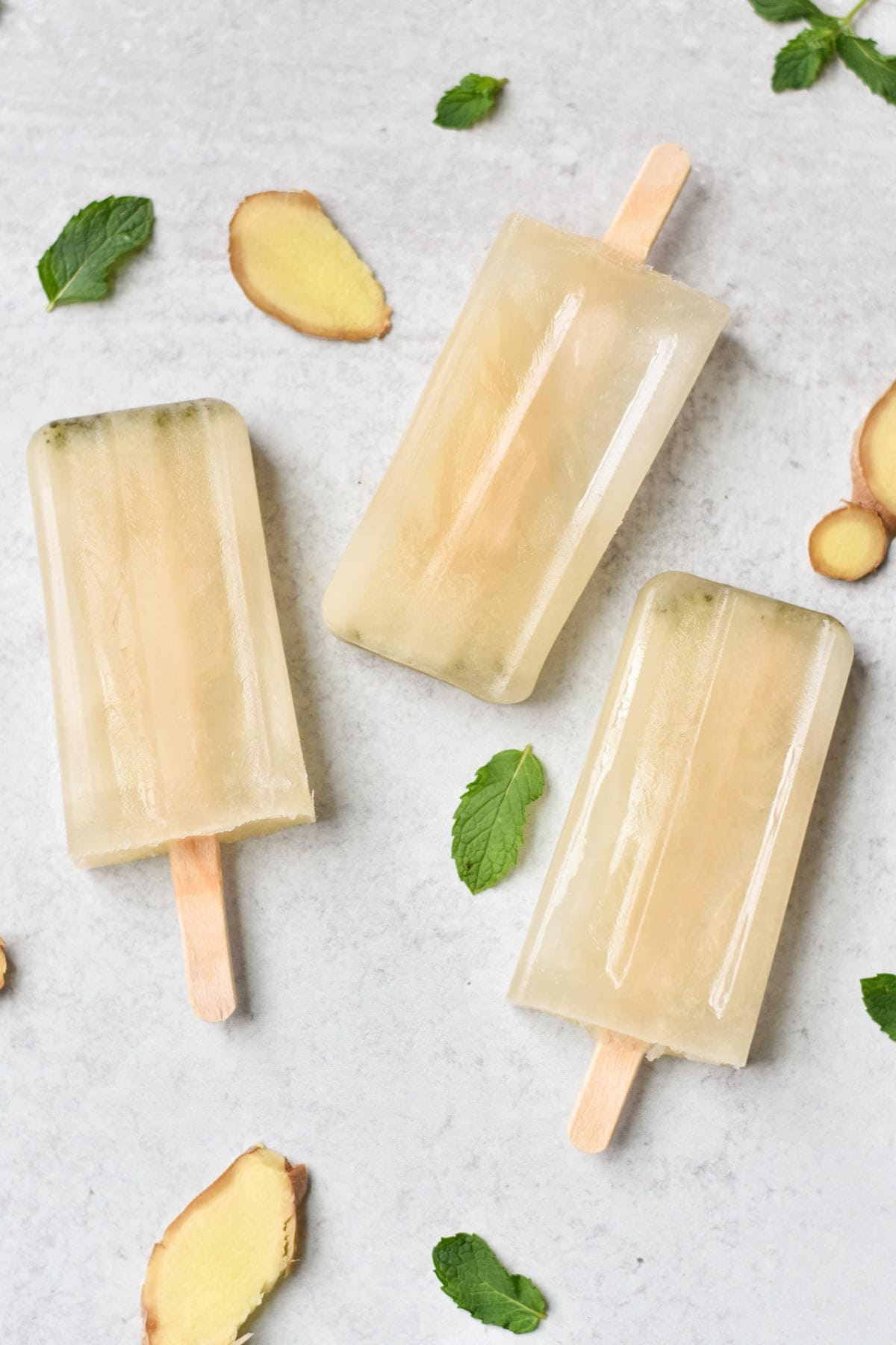 Hydration popsicles on a table with mint leaves and ginger pieces.