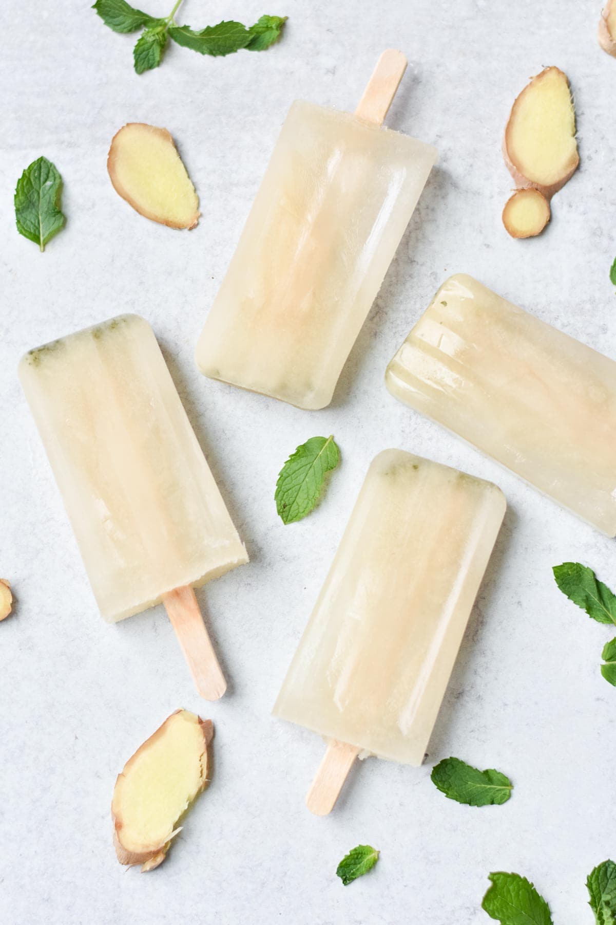 Hydration popsicles on a table with mint leaves and ginger pieces. 