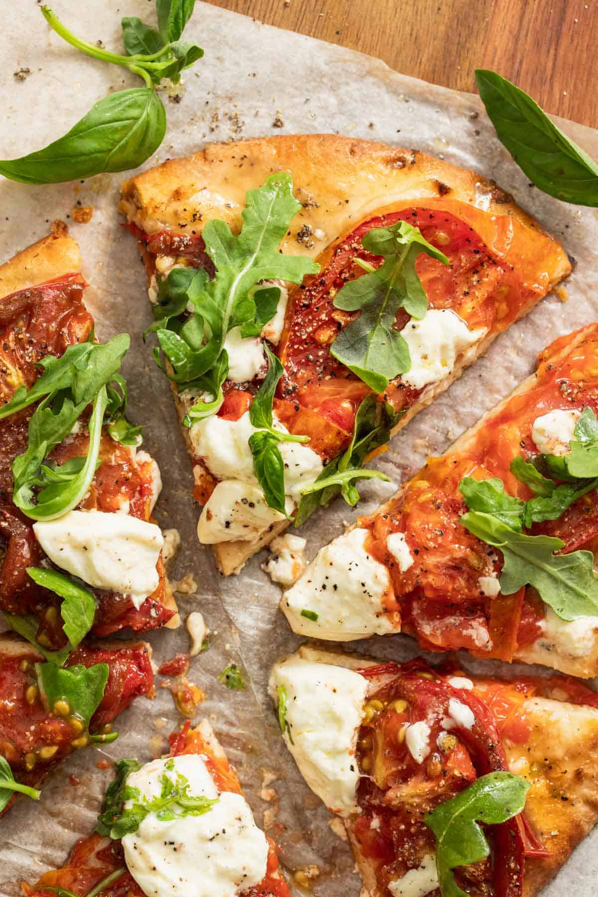 Slices of a naan pizza topped with burrata and arugula.