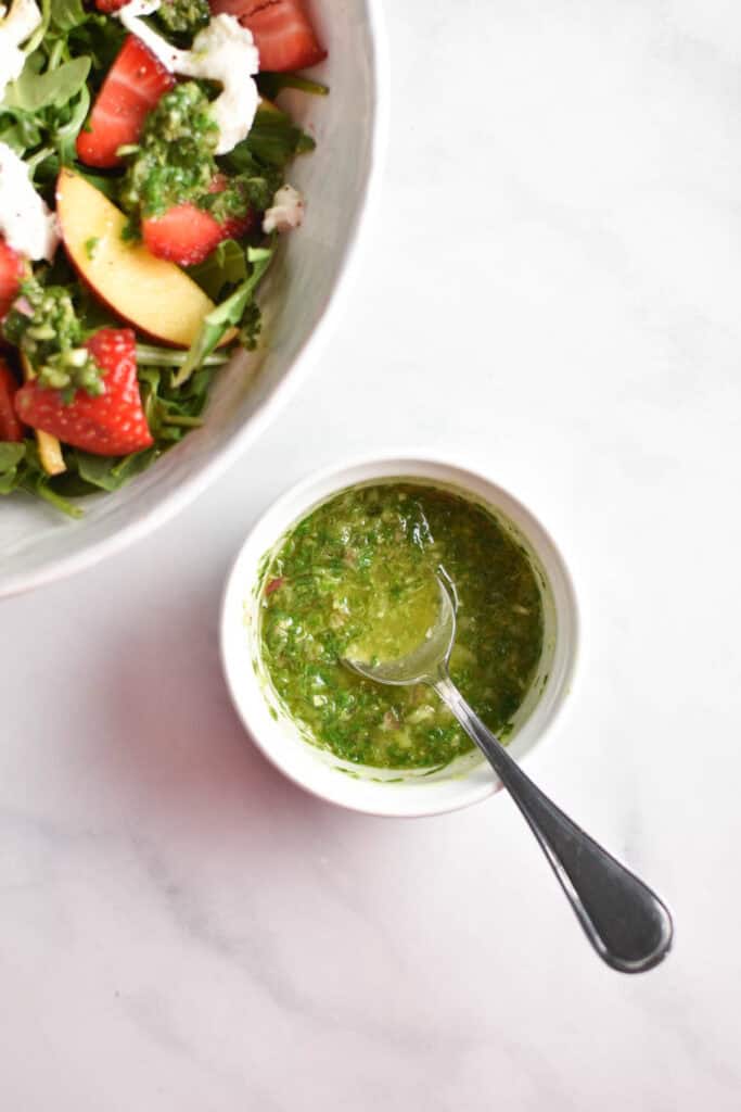 Basil vinaigrette in a cup with a spoon.