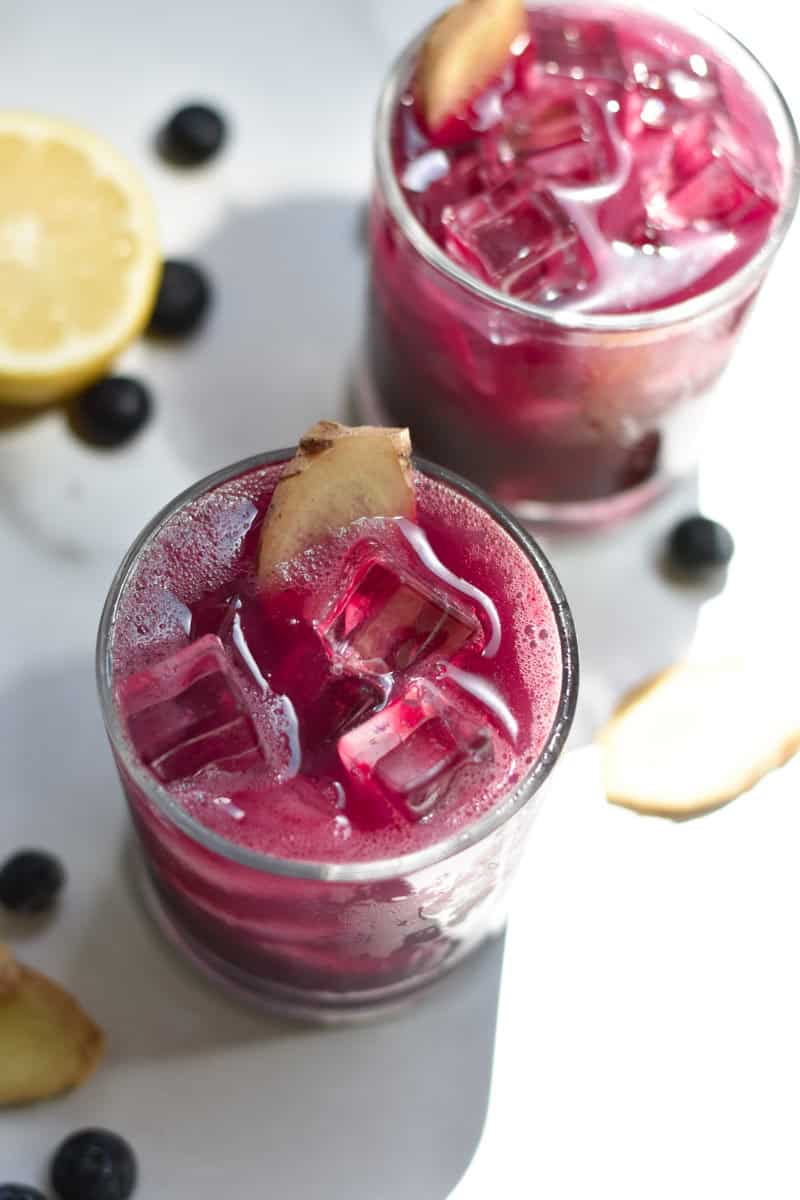 Sparkling water poured on top of a blueberry juice to create two mocktails. 