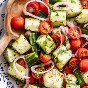 A wood spoon dipping into a bowl of mediterranean cucumber salad.