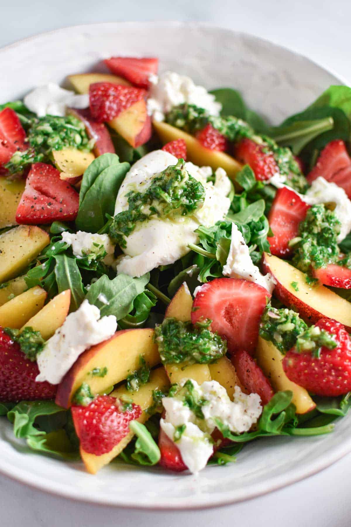 Burrata salad topped with peaches and strawberries. 