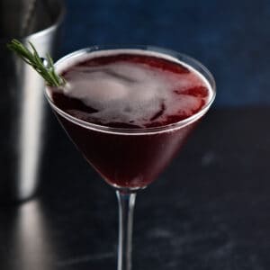 A sleepy girl mocktail in a martini glass in front of a silver shaker.