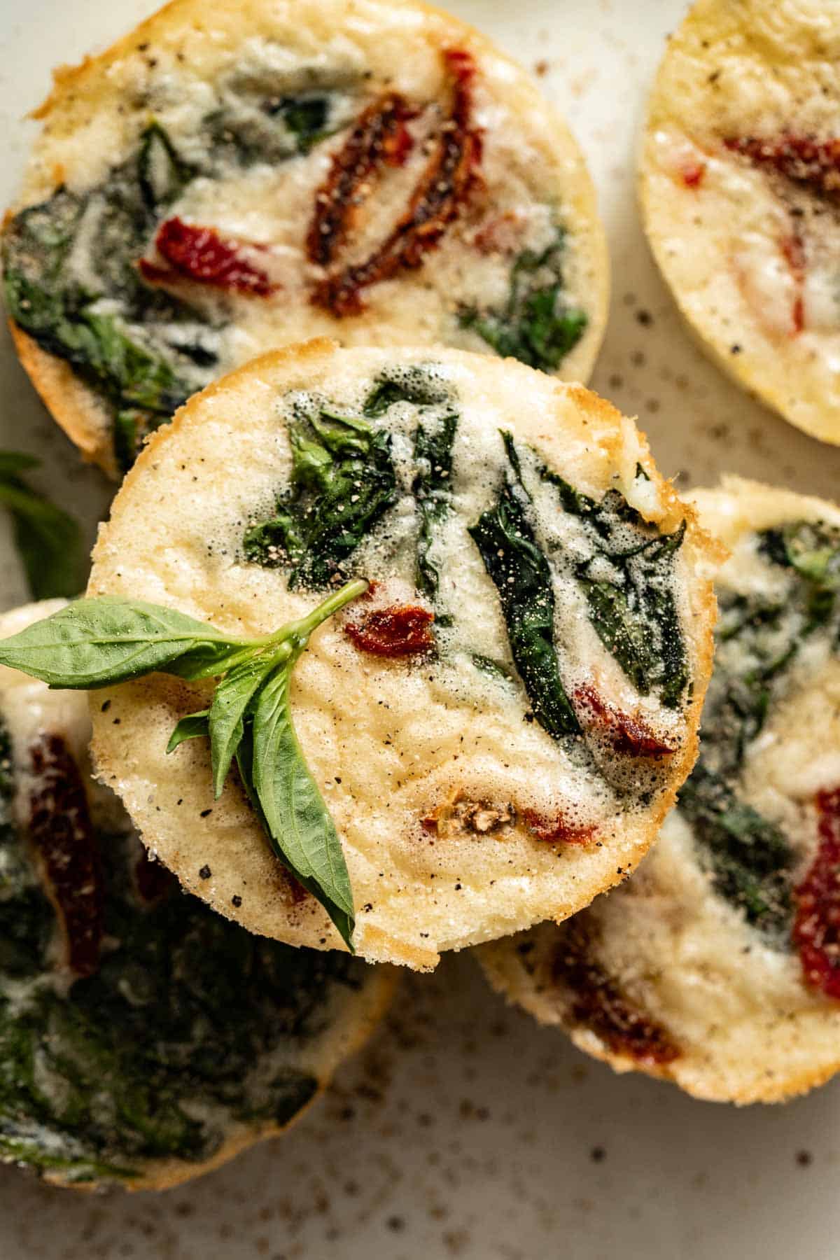 Cottage cheese egg bites stacked on top of each other with a small basil leave placed on top. 