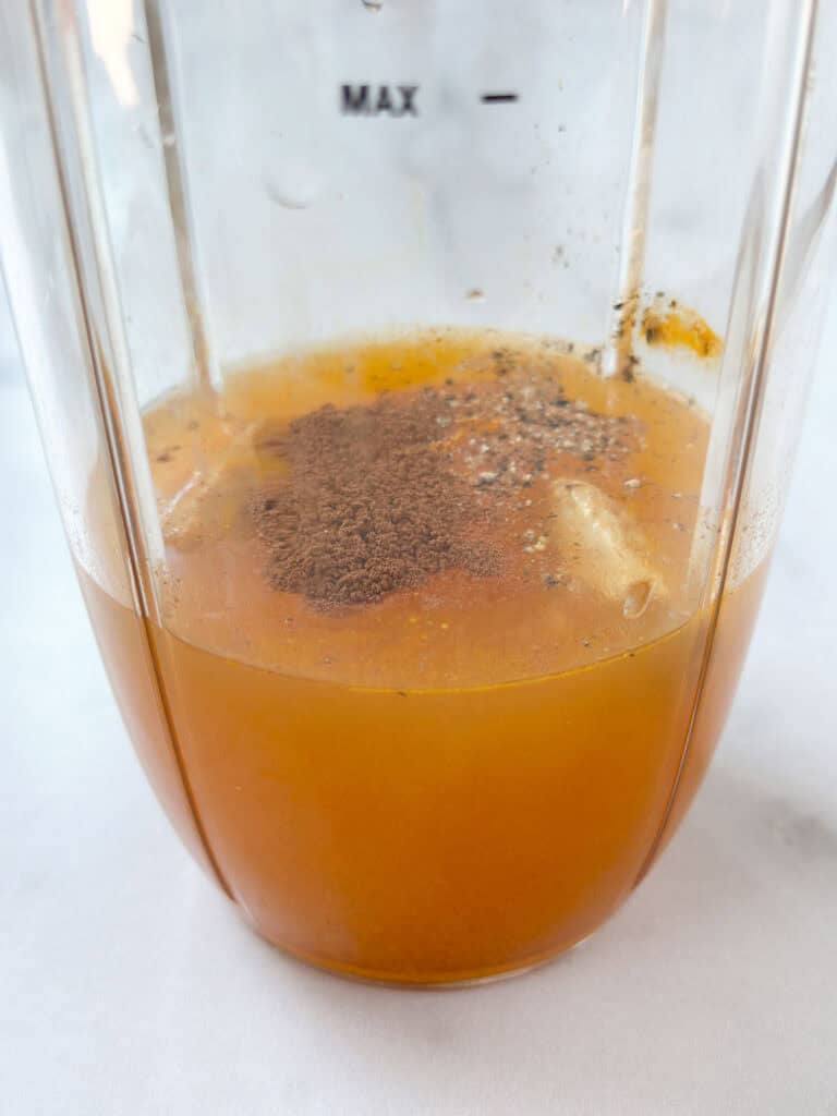 A blender filled with apple cider and spices.