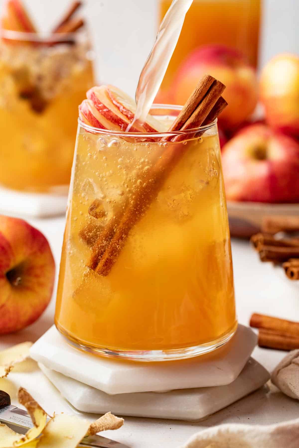 Pouring ginger ale into an apple cider mocktail.