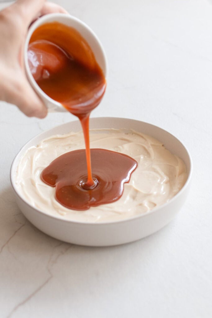 Pouring caramel into the cream cheese dip bowl.