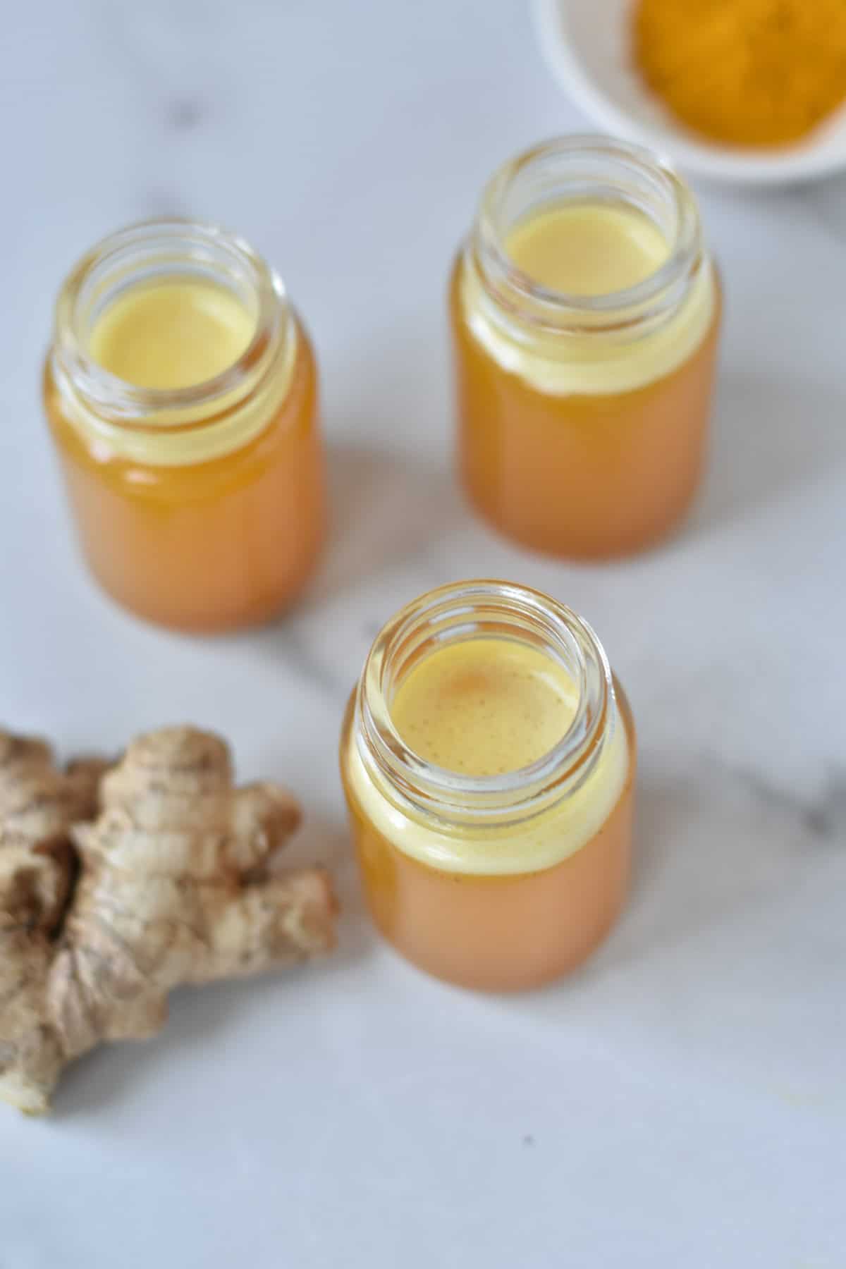 Overhead of glass jars filled with ginger turmeric juice.