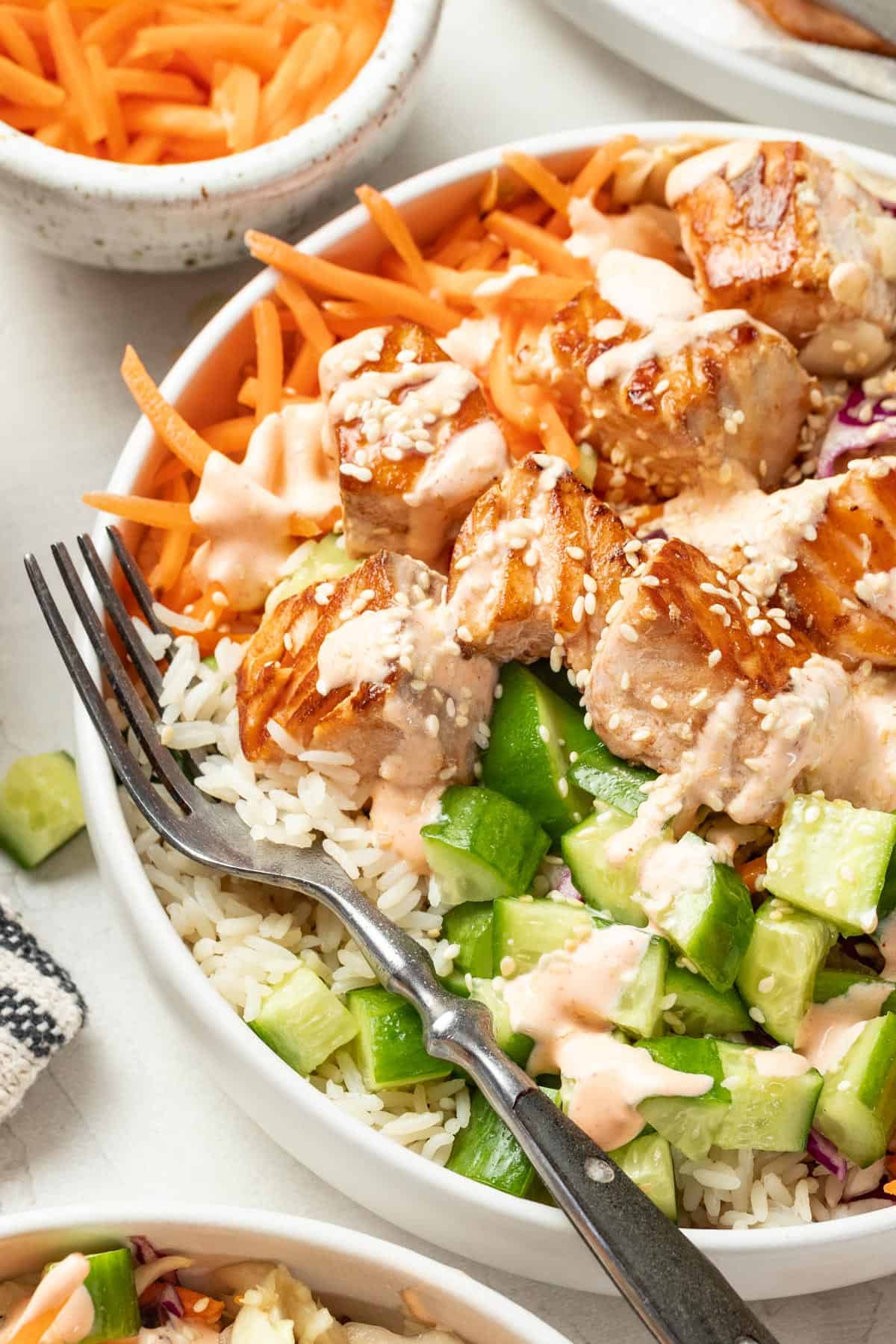 Spicy mayo sauce on top of a salmon bowl with a fork.