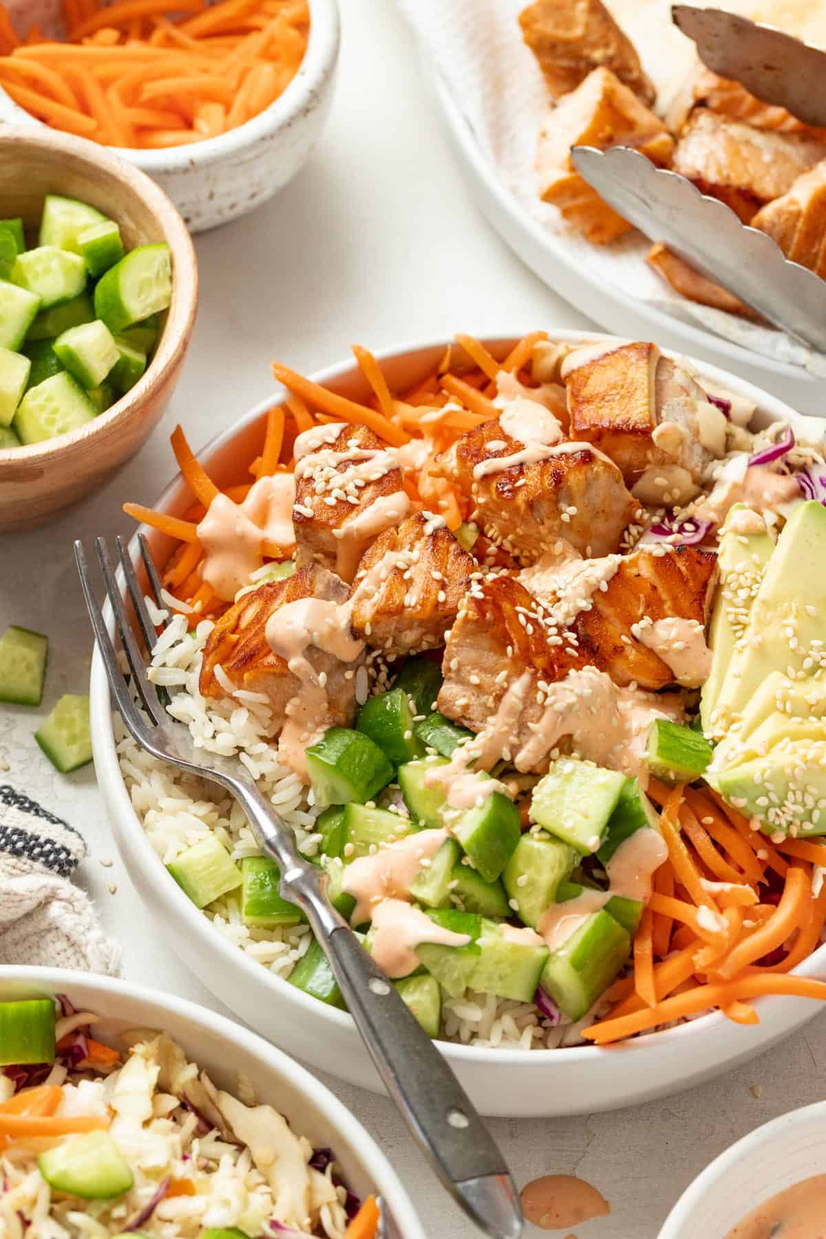 Drizzling spicy mayo sauce on top of the salmon bowls.