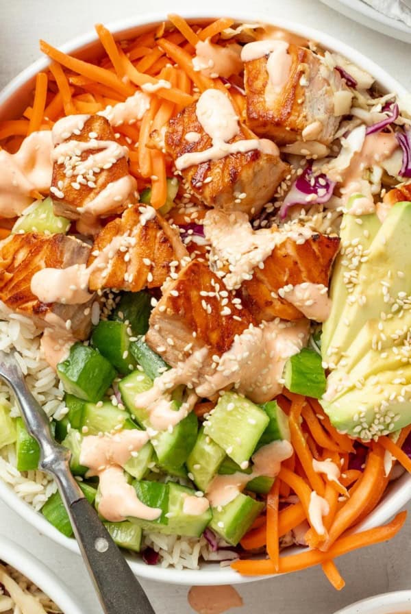 Salmon rice bowls topped with spicy mayo and sesame seeds.