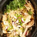 Chicken enchiladas after being cooked in the slow cooker with a wood spoon dipping in to serve.