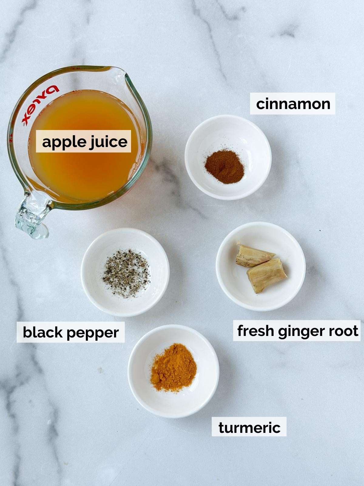 Apple juice, turmeric, ginger, pepper, and cinnamon on a white background.