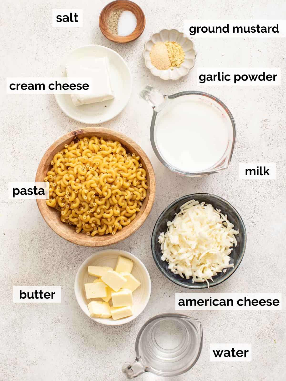 Ingredients for crockpot mac and cheese with cream cheese and american cheese on a white background.