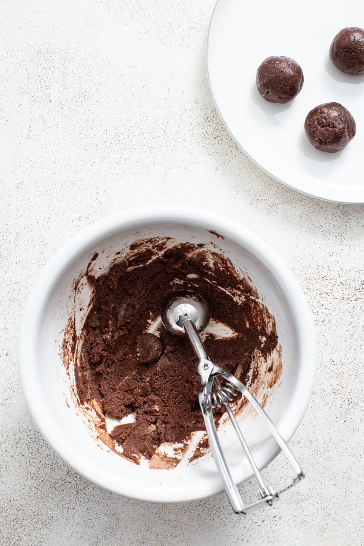 Scooping the brownie mixture into balls with a cookie scoop.
