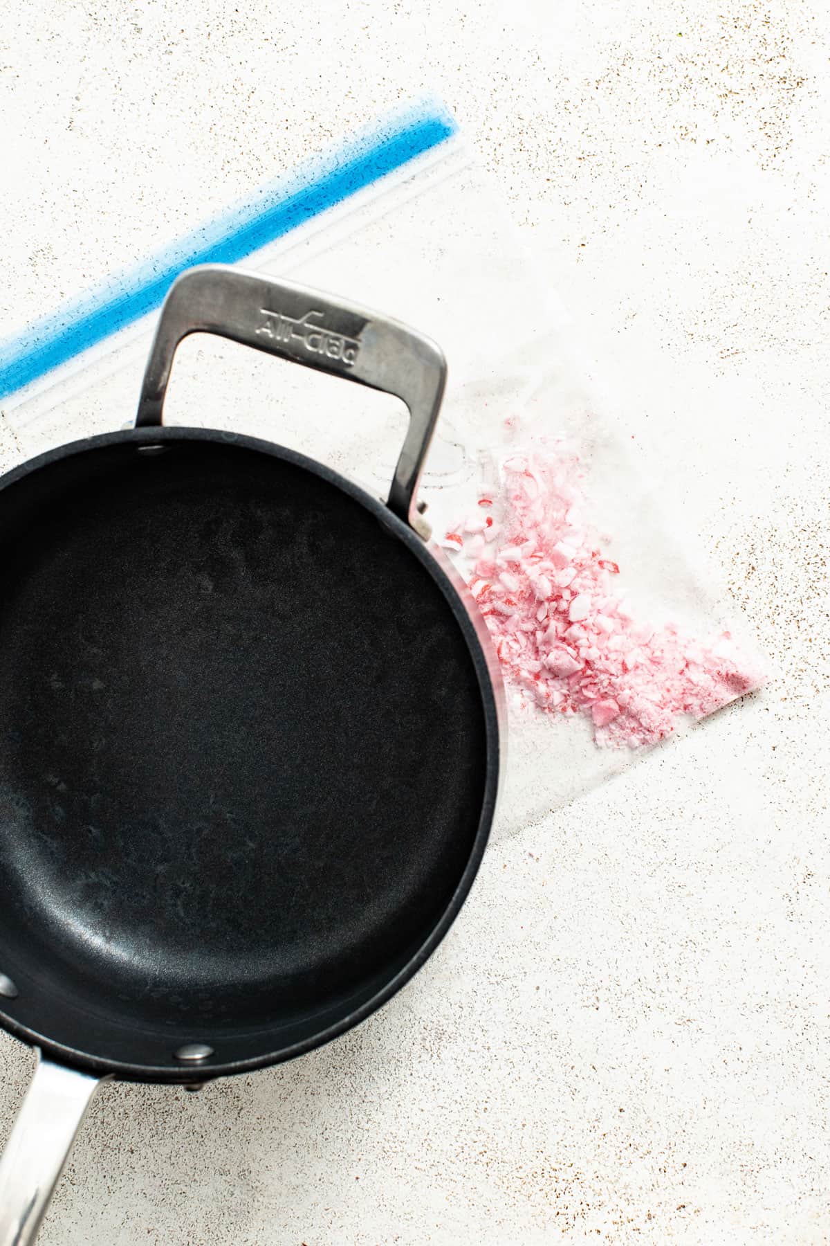 A pot crushing peppermint candies in a plastic bag.