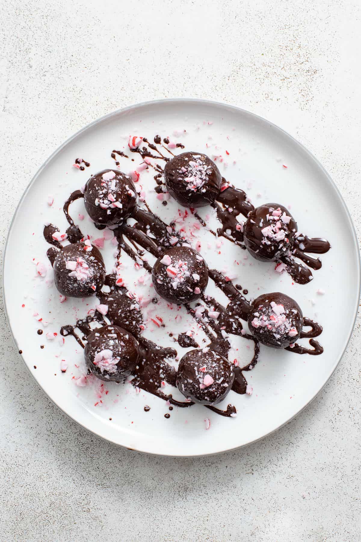 A plate of brownie balls topped with carob chocolate and peppermint.