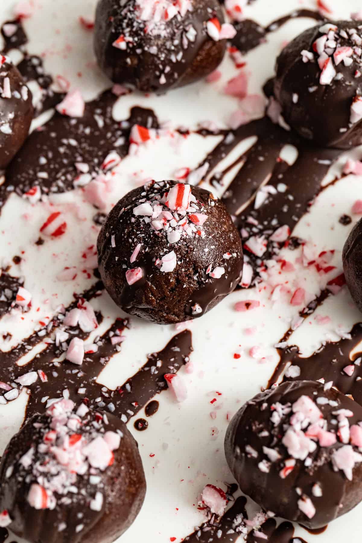 Brownie balls with chocolate sauce drizzled on top and crushed peppermint candies on top.
