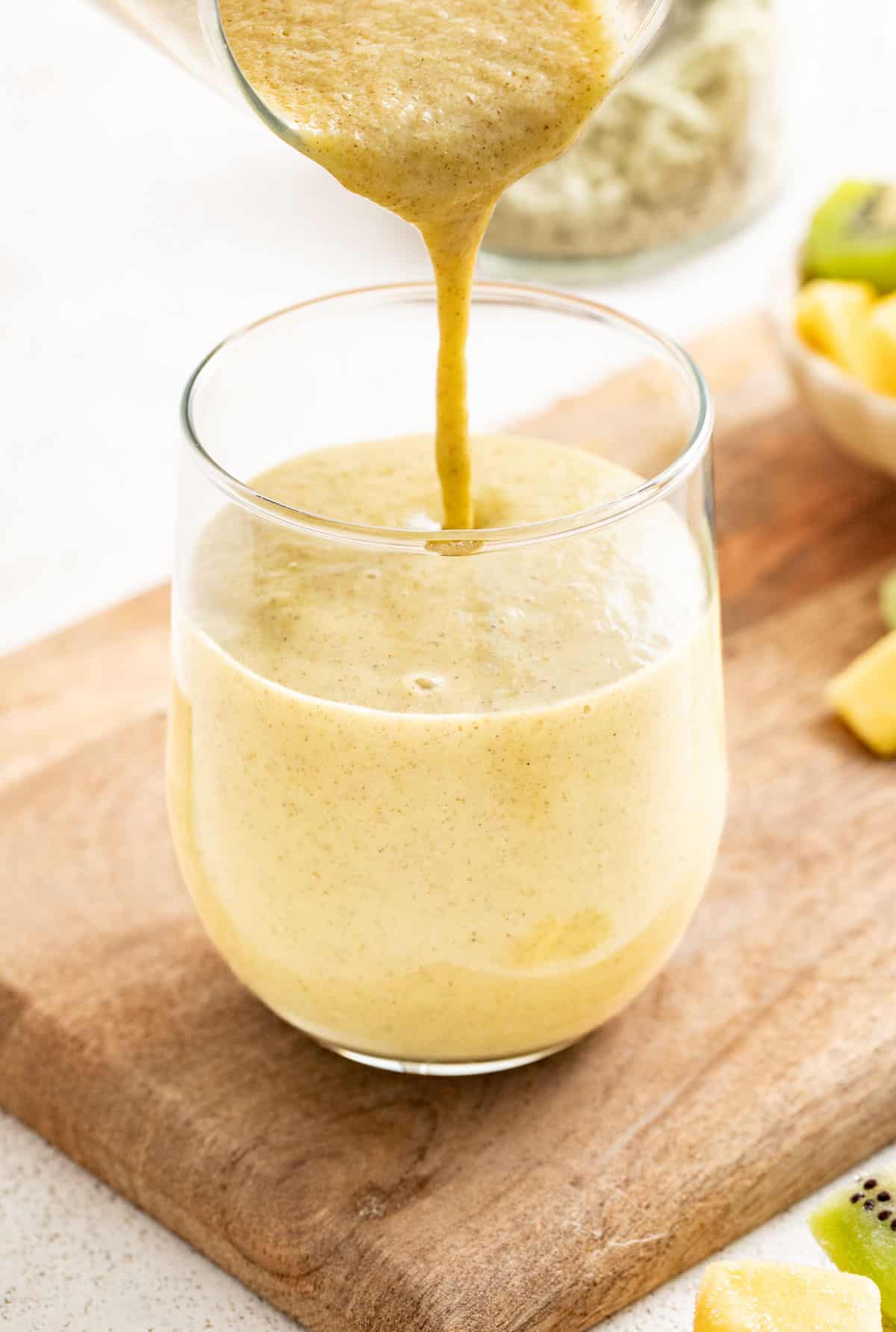 Pouring a ginger smoothie into a glass.