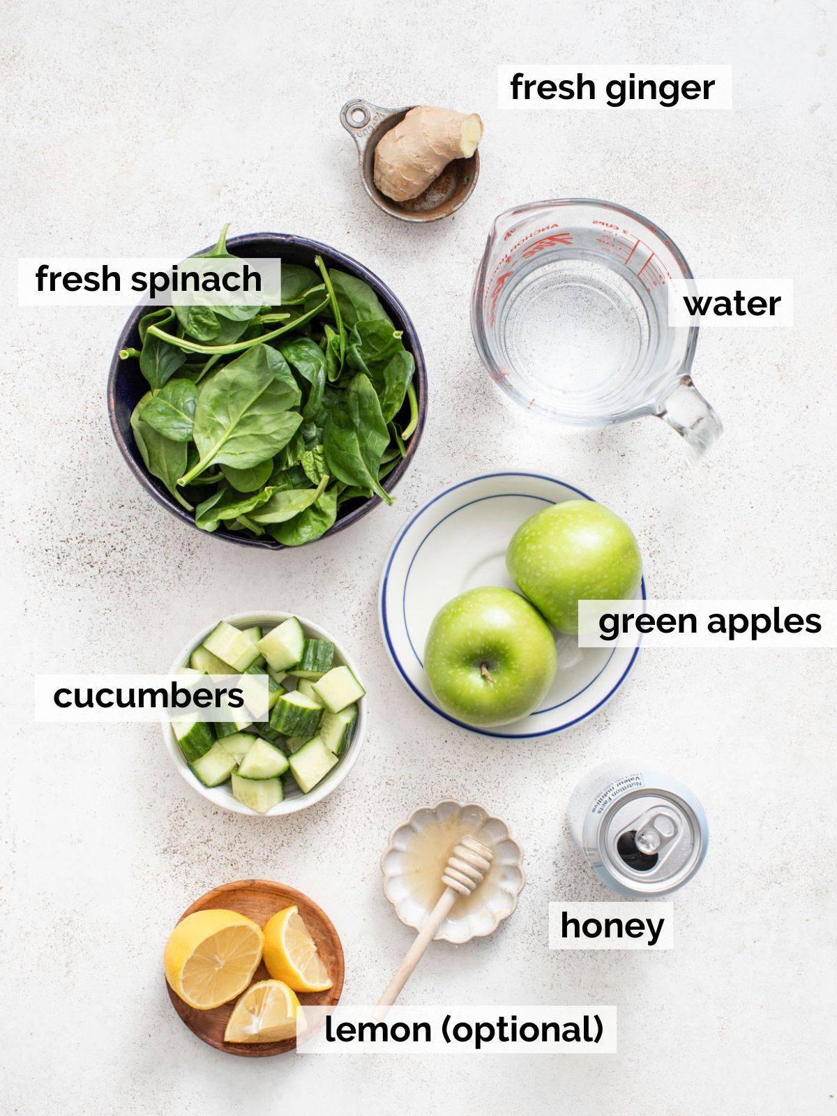 Ingredients for green apple juice including cucumber and ginger on a white background.