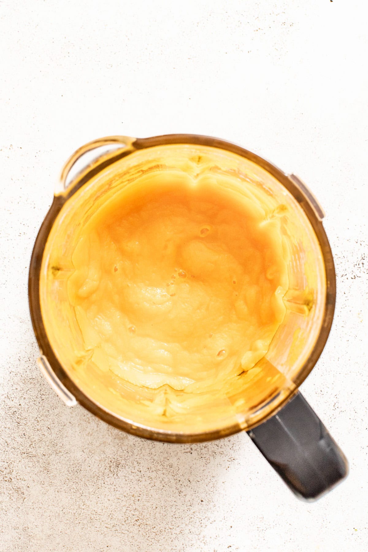 An orange vegetable sauce that has been blended till smooth in a blender.