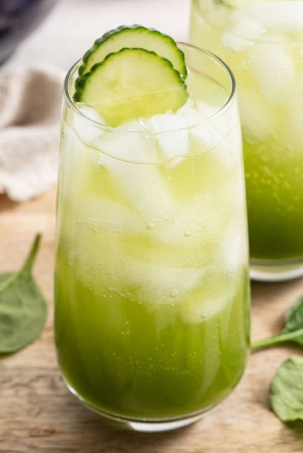 Green mocktail with cucumbers at the top.