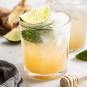 Homemade ginger ale with lime slices and ice in a clear glass.