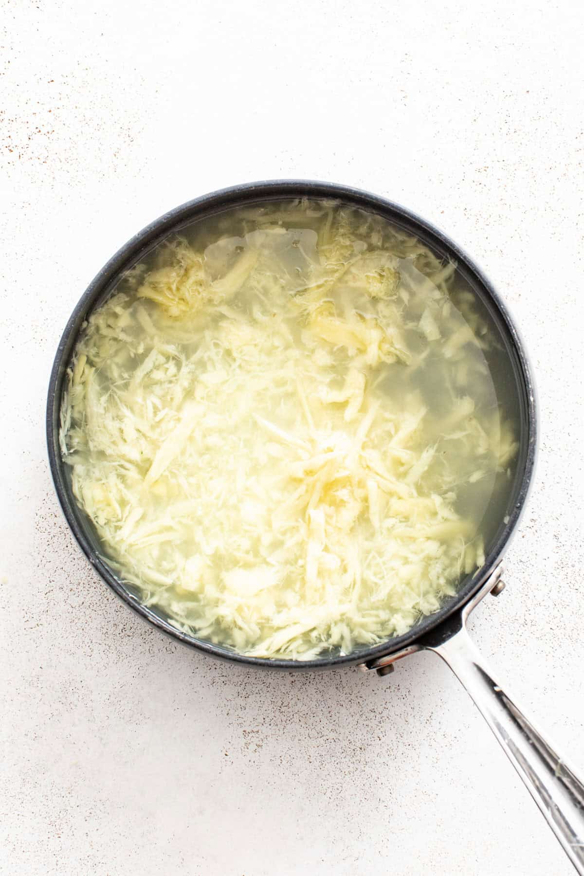 Simmering water and fresh ginger together in a small pot.