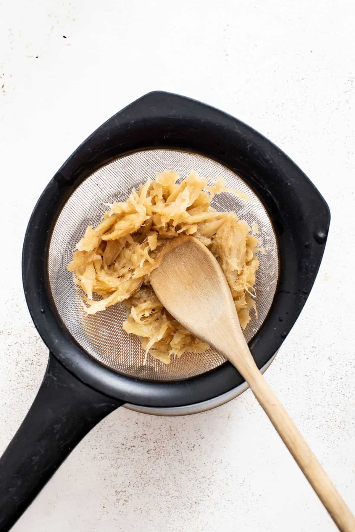 Straining ginger pieces out of the ginger juice.