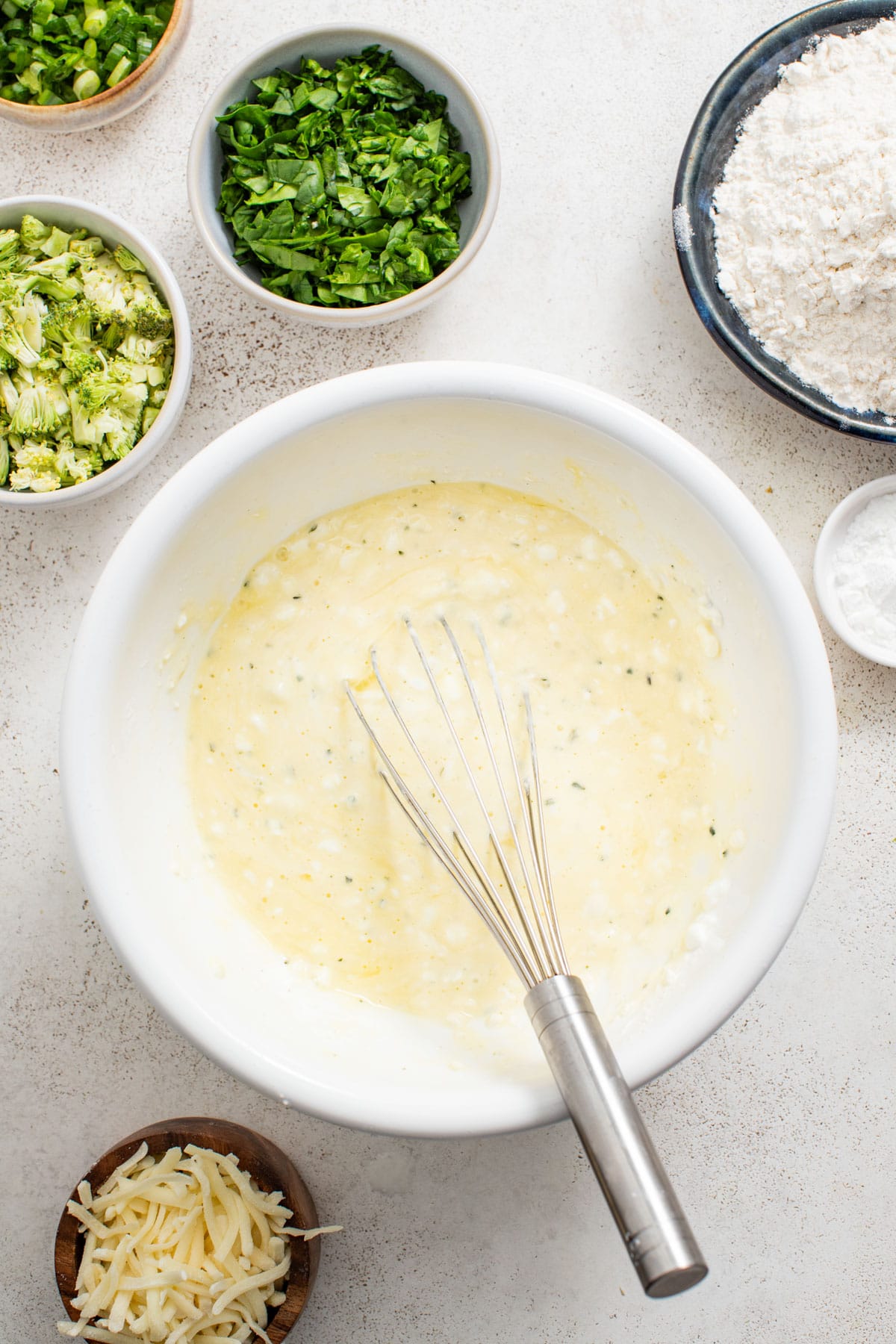 Whisking cottage and boursin cheese together in a bowl with eggs.