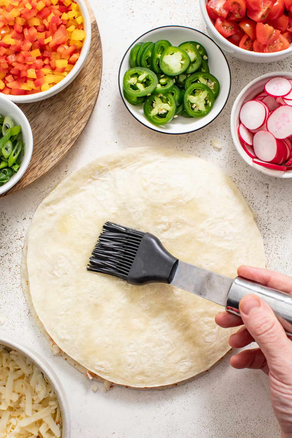 Brushing the outer tortilla of a quesadilla with oil before cooking.