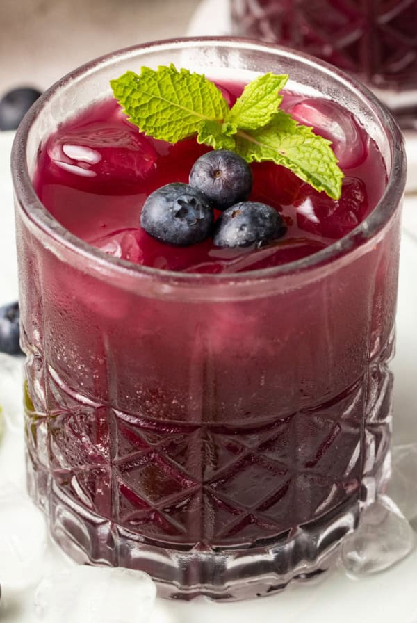 Blueberry mojito mocktail topped with blueberries and mint in a glass with ice.