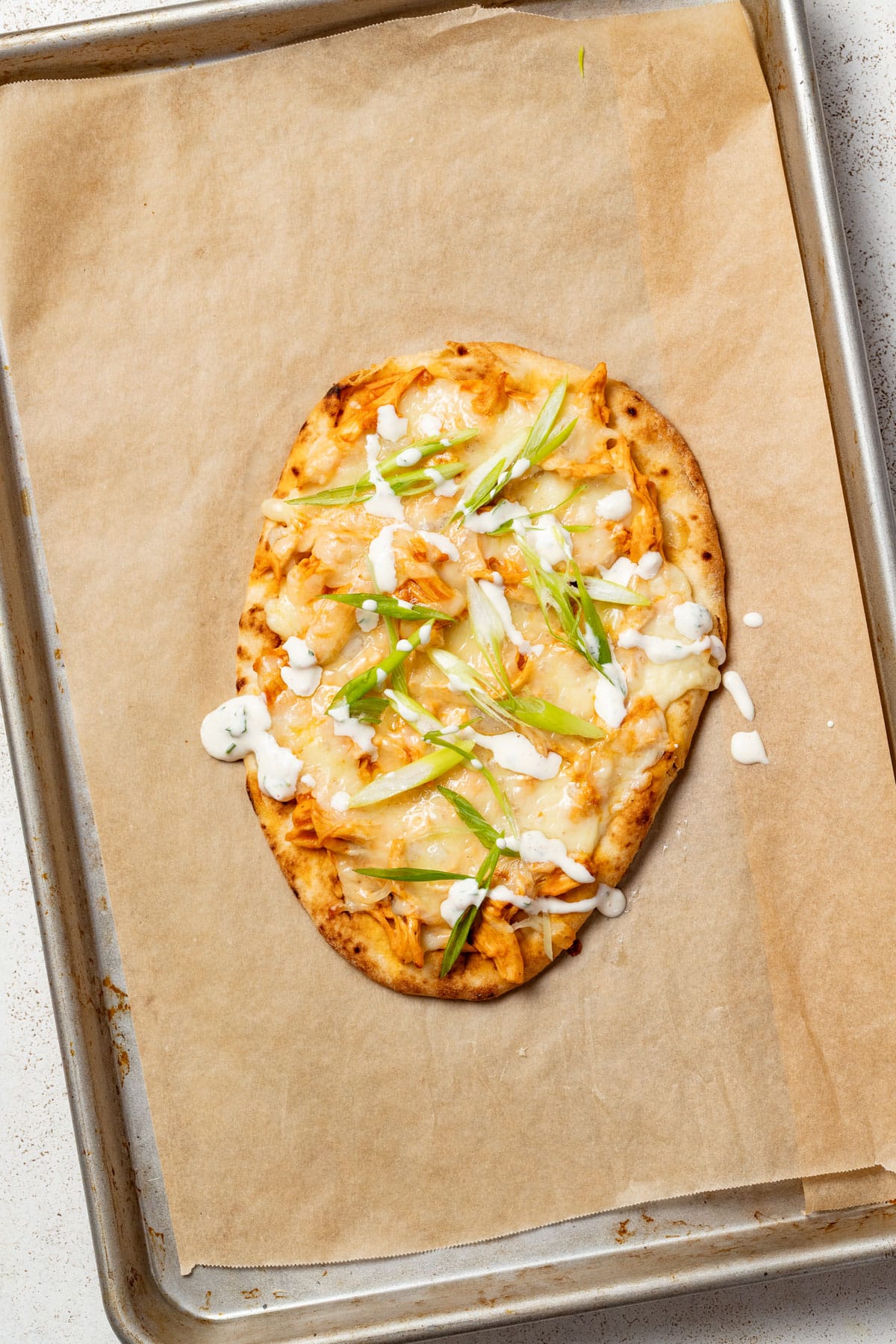 Flatbread topped with green onion and ranch after being baked and cooled.