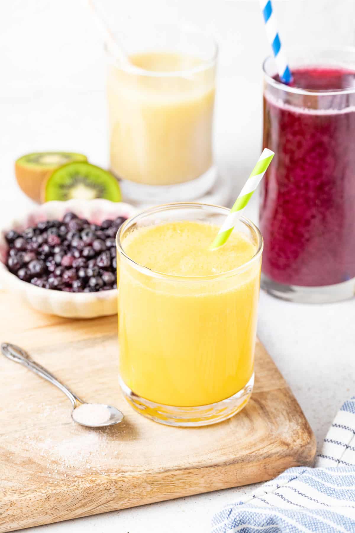 Mango electrolyte drink in a glass next to berries.