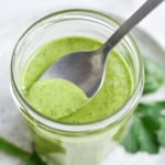A spoon dipping into a Mediterranean dressing.