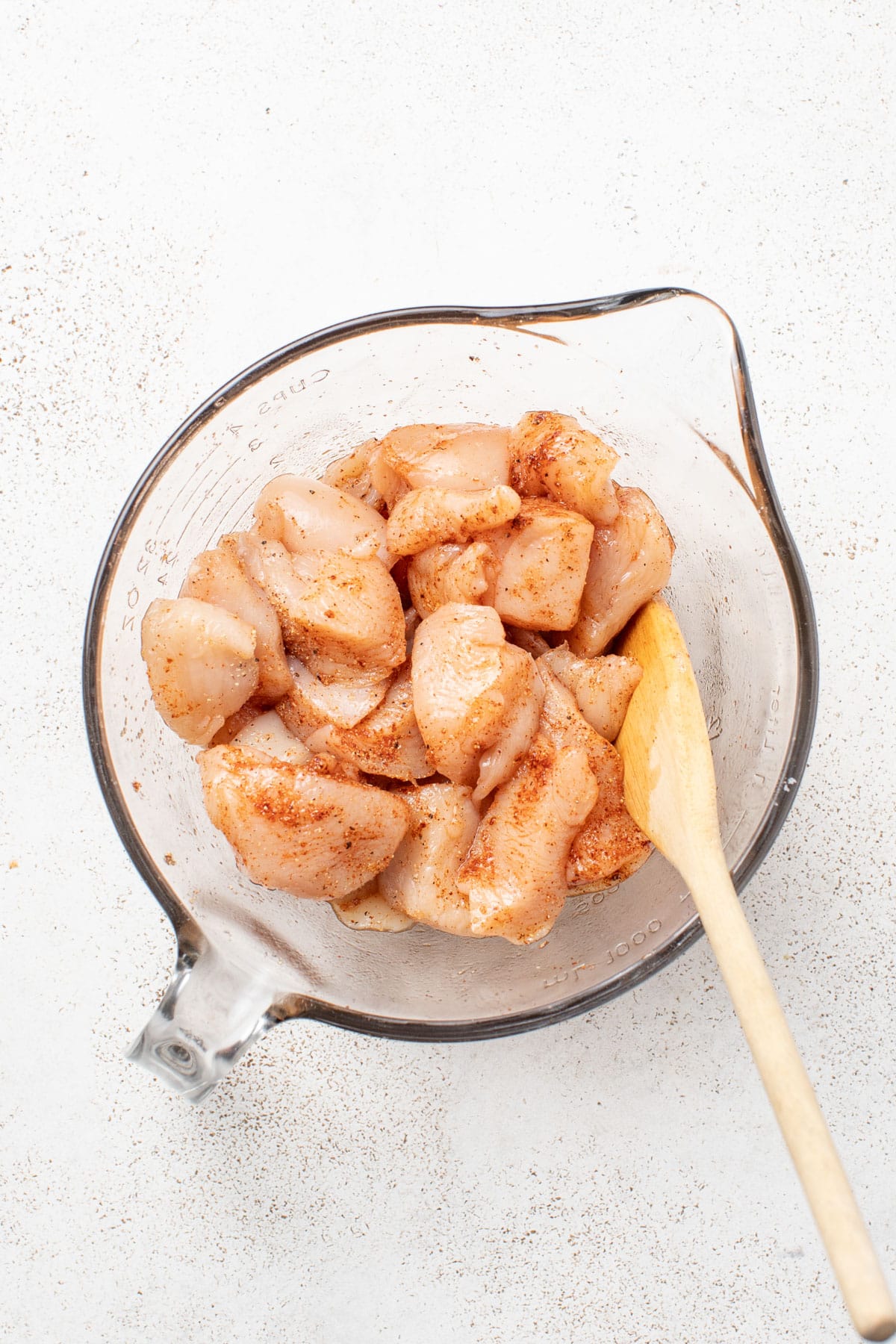 Mixing the raw chicken and spices together in a bowl.