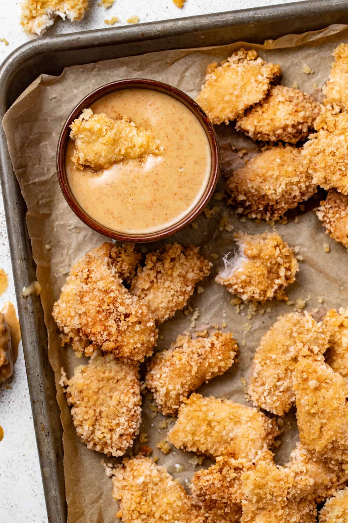 Crispy air fried chicken nuggets on a platter being dipped into a honey bbq sauce.