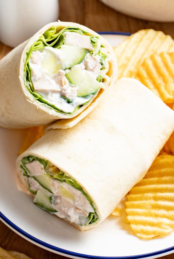 A chicken wrap with cucumber and lemon on a plate.