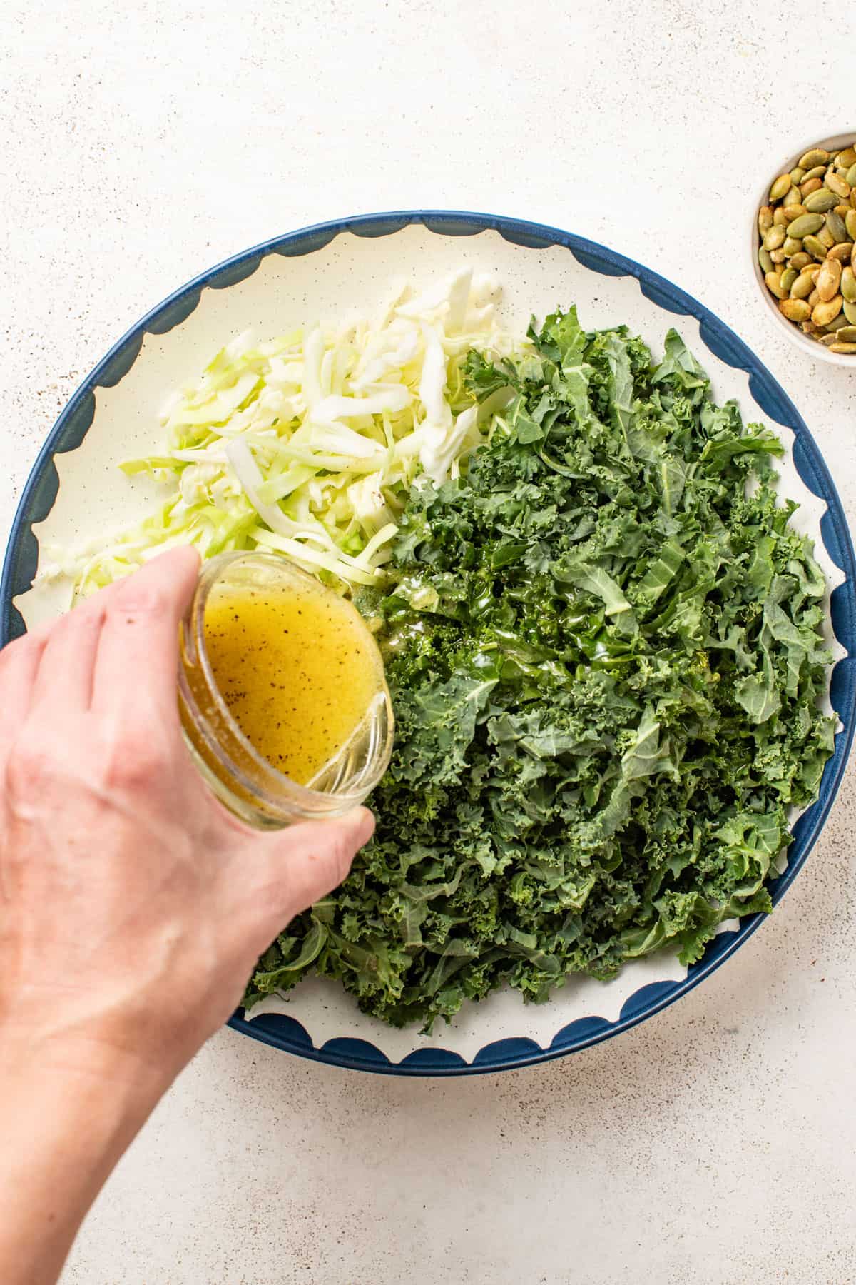 Pouring dressing into a kale salad.