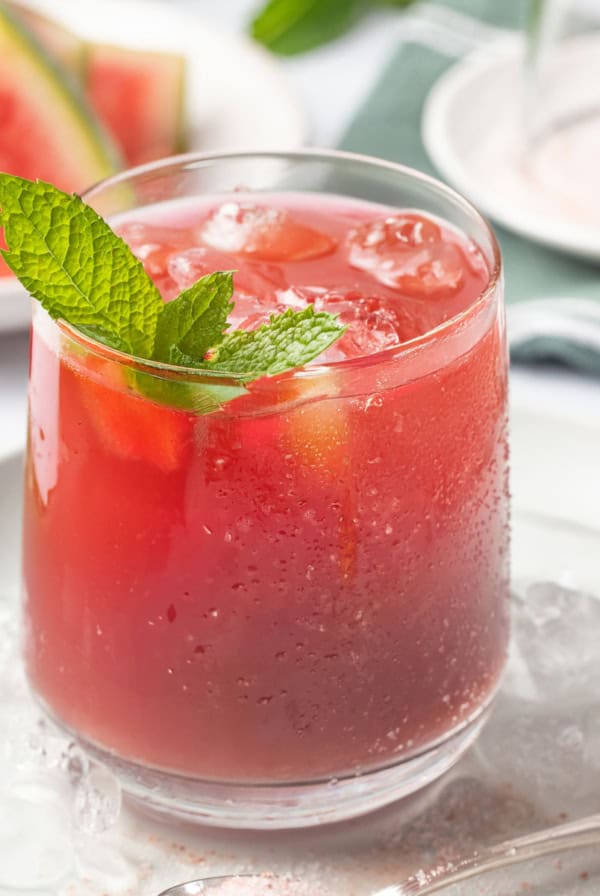 A glass of watermelon juice with mint sprig on top.