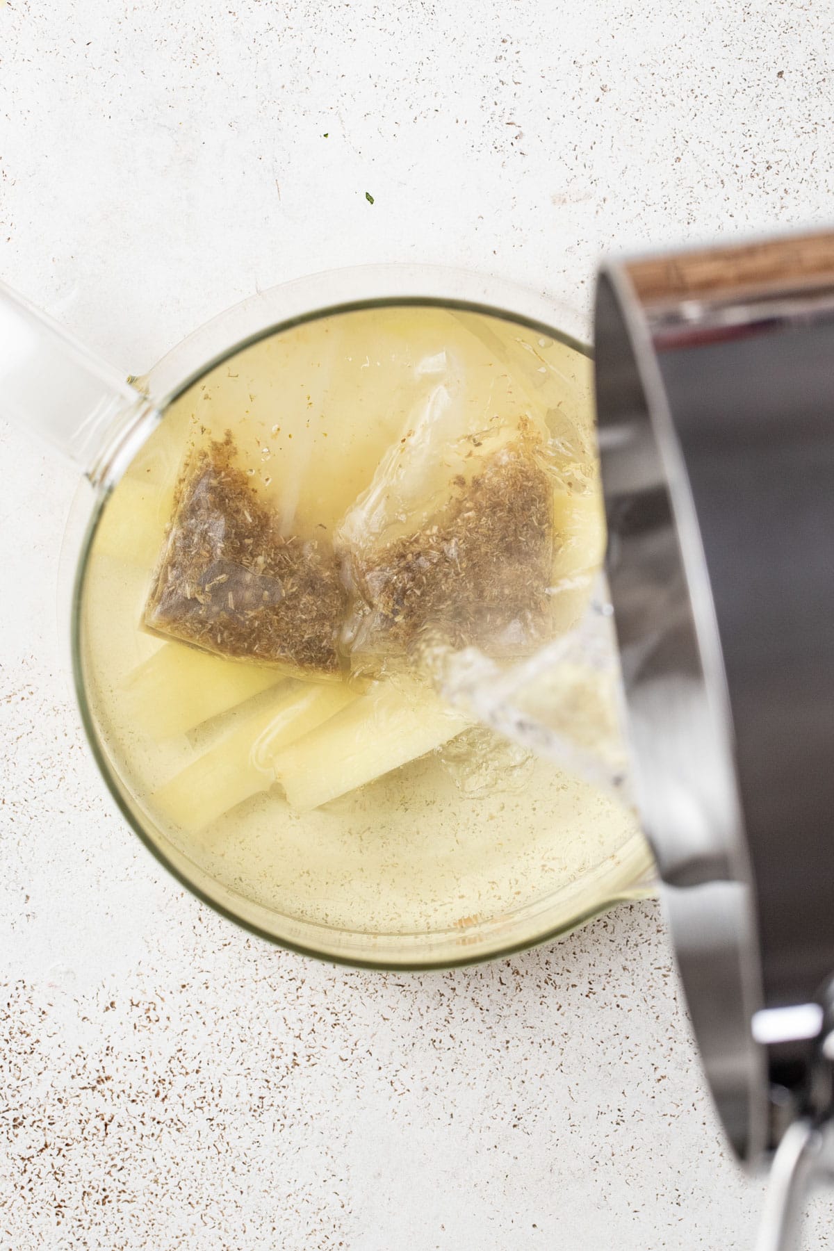 Pouring hot water over the tea bags and ginger.