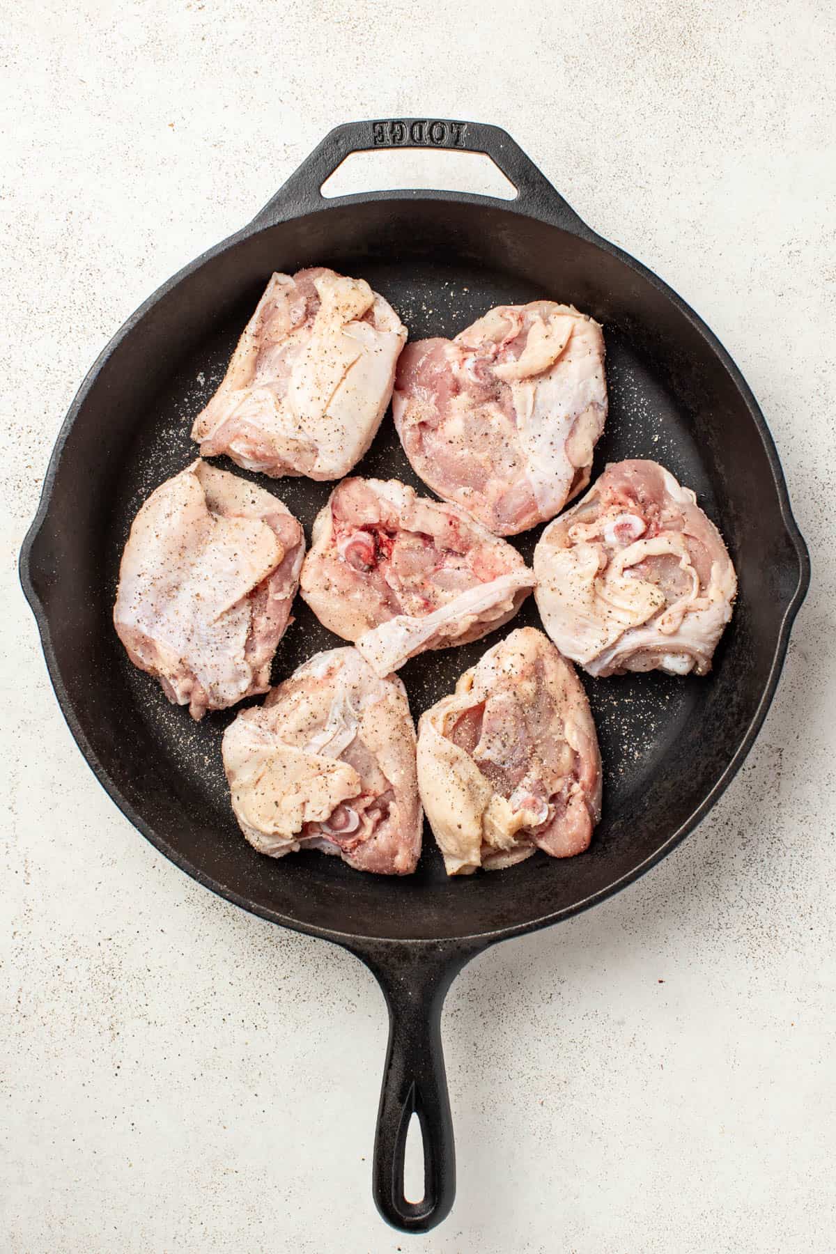 Searing chicken thighs skin side down in a cast iron pan.