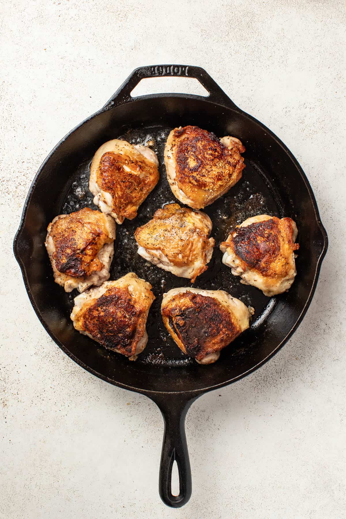 Chicken thighs after being seared in a cast iron pan.