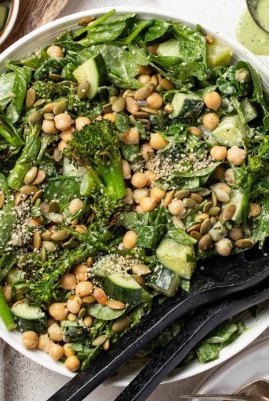 Spinach salad with chickpeas and cucumbers tossed in a creamy dressing.